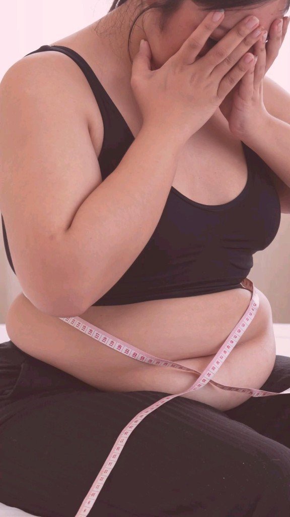 Woman holding a measuring tape around her waist, feeling frustrated that nothing is changing